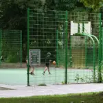 Eingezäunter Basketballplatz mit zwei Körben in einer Grünanlage