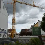 Baukran über einer innerstädtischen Baustelle zwischen Wohnhäusern