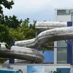 Große Edelstahl-Wasserrutsche an der Außenseite eines Schwimmbads