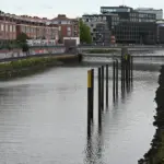 Flusslauf mit Wehr, Uferbefestigung und Wohnhäusern am Ufer